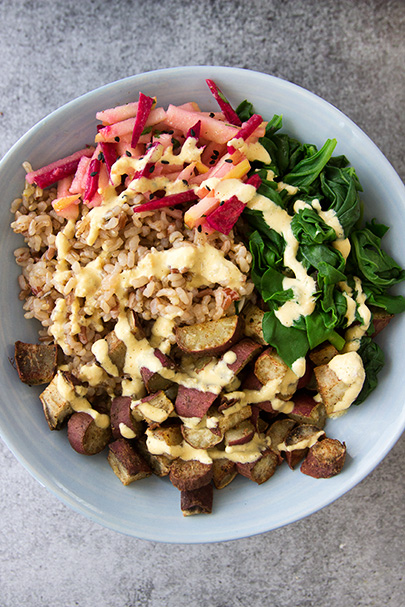 Warming Winter Salad Bowl - a delicious mix of brown rice, cinnamon sweet potatoes, garlicky spinach, apple & beet slaw, and a creamy carrot-tahini dressing. Simply heaven! www.sprinkleofgreen.com